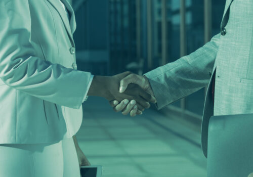 Two business professionals shaking hands, symbolizing trust and verified partnerships through Know Your Business (KYB) checks.