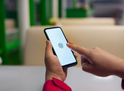 Hand holding smartphone displaying biometric fingerprint scan for secure mobile identity verification.